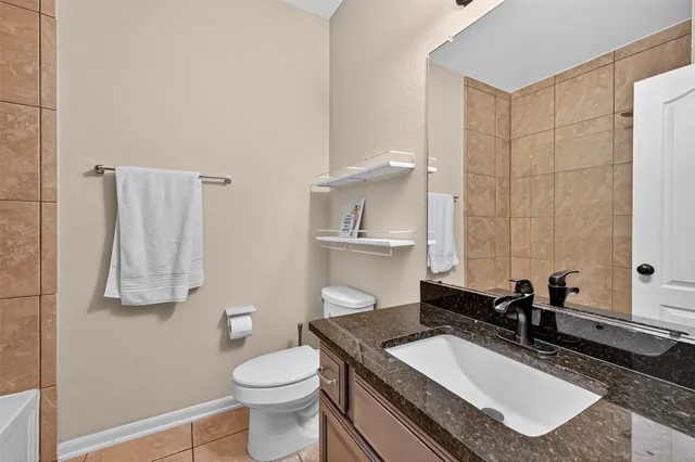 a bathroom with a granite countertop sink a toilet and a mirror
