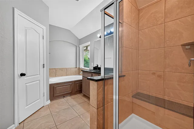 a bathroom with a tub a sink a mirror and a shower