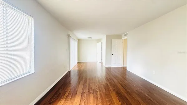 a view of an empty room with wooden floor and a window