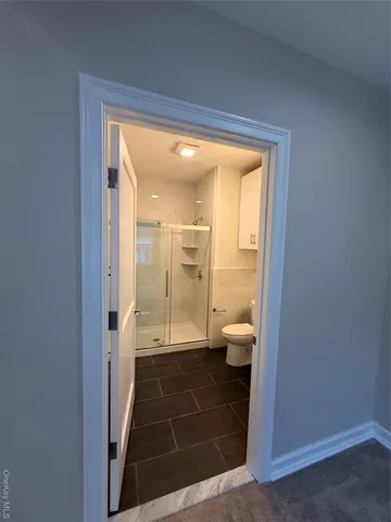 a bathroom with a glass door shower and a toilet