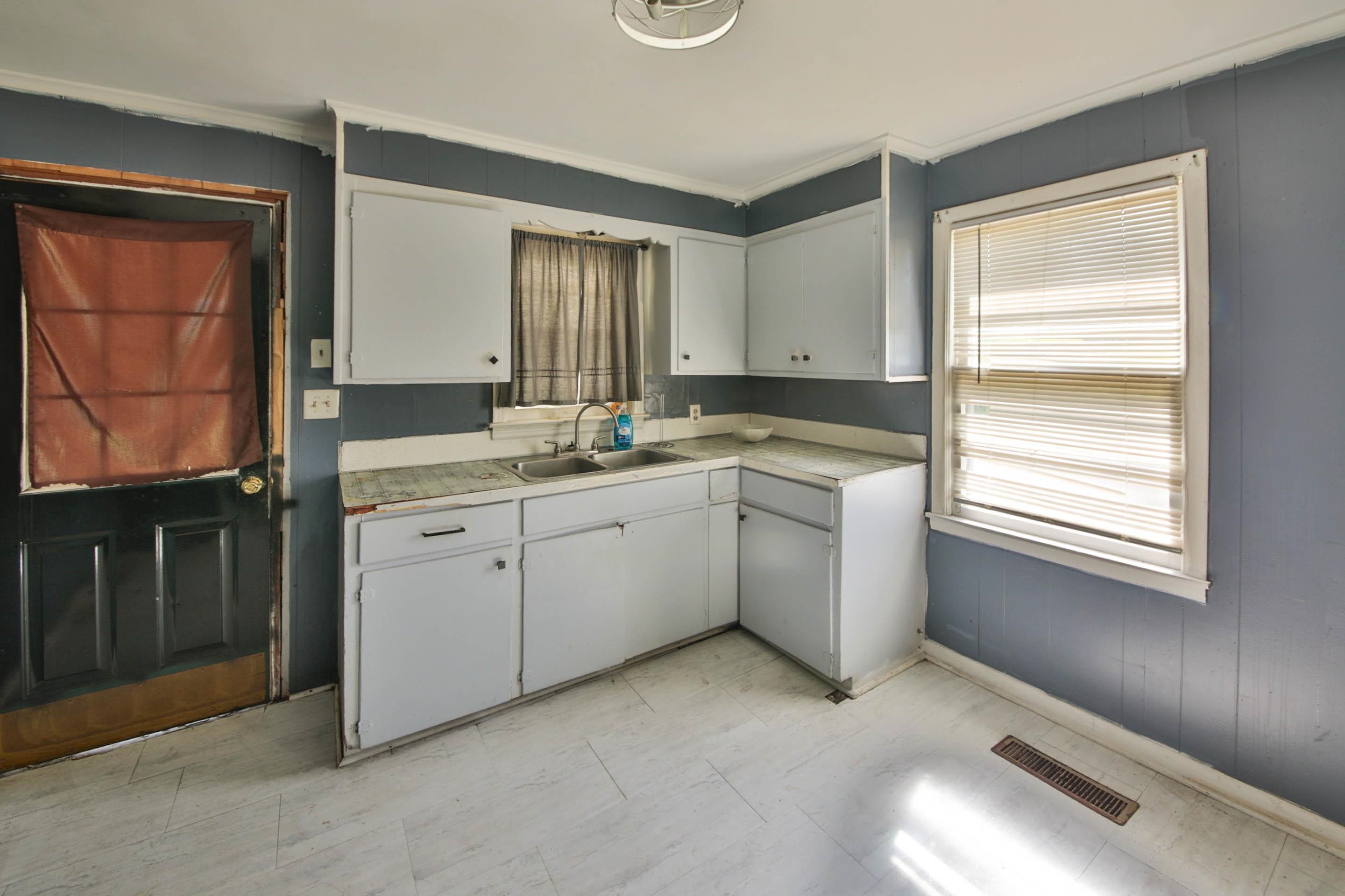 322 Highland Street Ripley, TN 38063 - Photo 7 of 12 Kitchen with light countertops, white cabinetry, wood walls, and ornamental molding