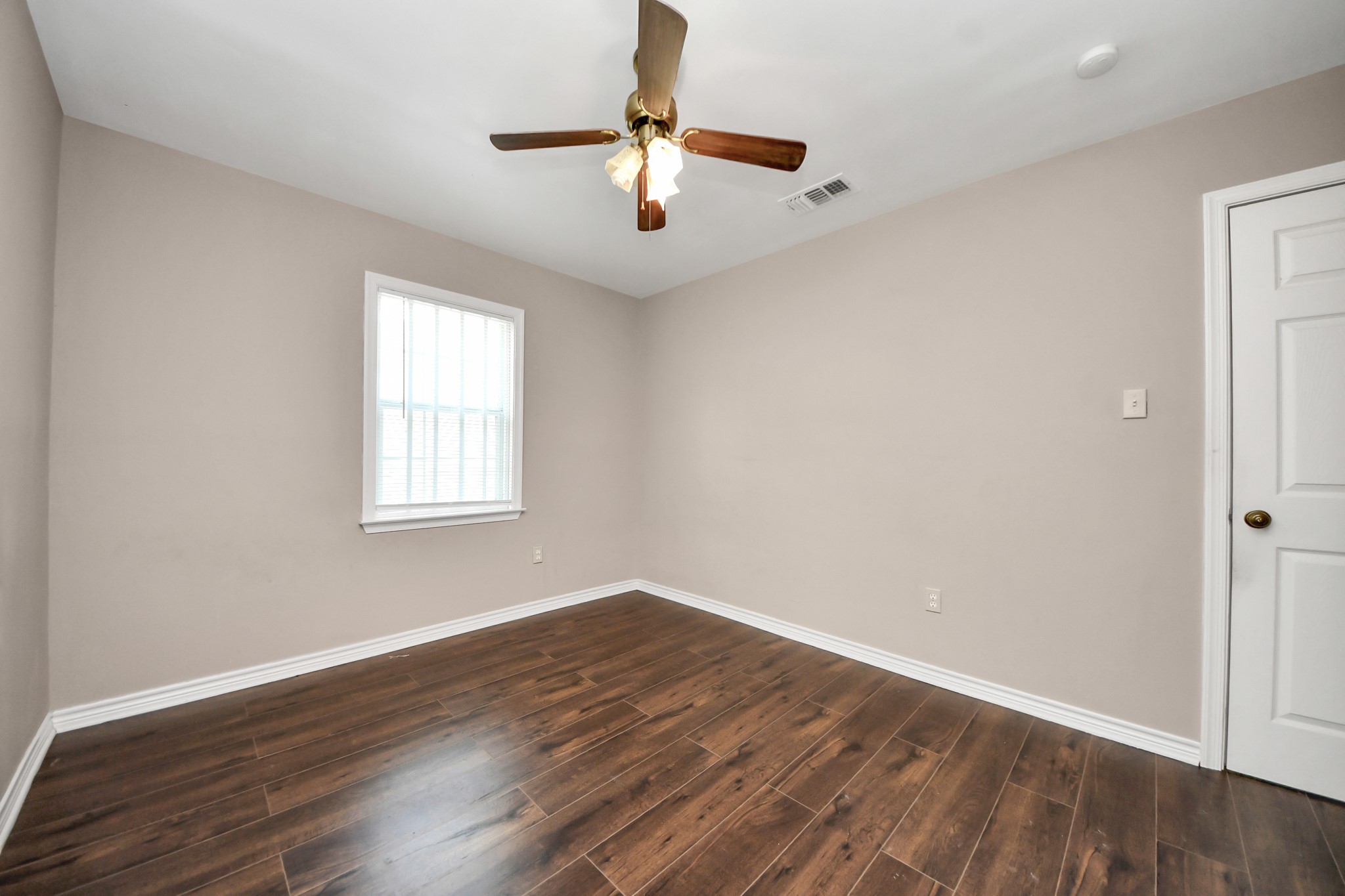 5202 Pensdale Street Houston, TX 77033 - Photo 17 of 32 an empty room with wooden floor chandelier fan and windows
