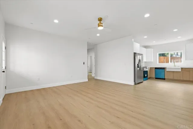 a view of an empty room with wooden floor and windows