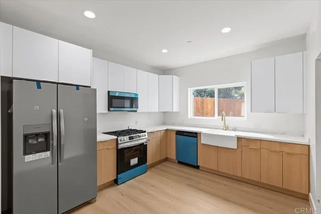 a kitchen with stainless steel appliances granite countertop a refrigerator a sink dishwasher a stove and white cabinets with wooden floor