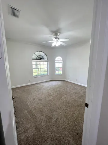 en empty room with windows and ceiling fan