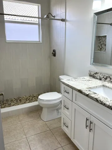 a bathroom with a granite countertop toilet a sink and a mirror