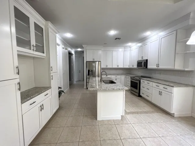 a large kitchen with stainless steel appliances kitchen island granite countertop a stove and a sink
