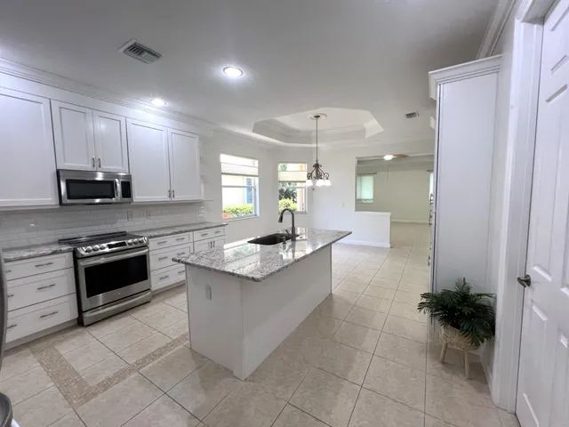a large kitchen with stainless steel appliances a stove sink and cabinets