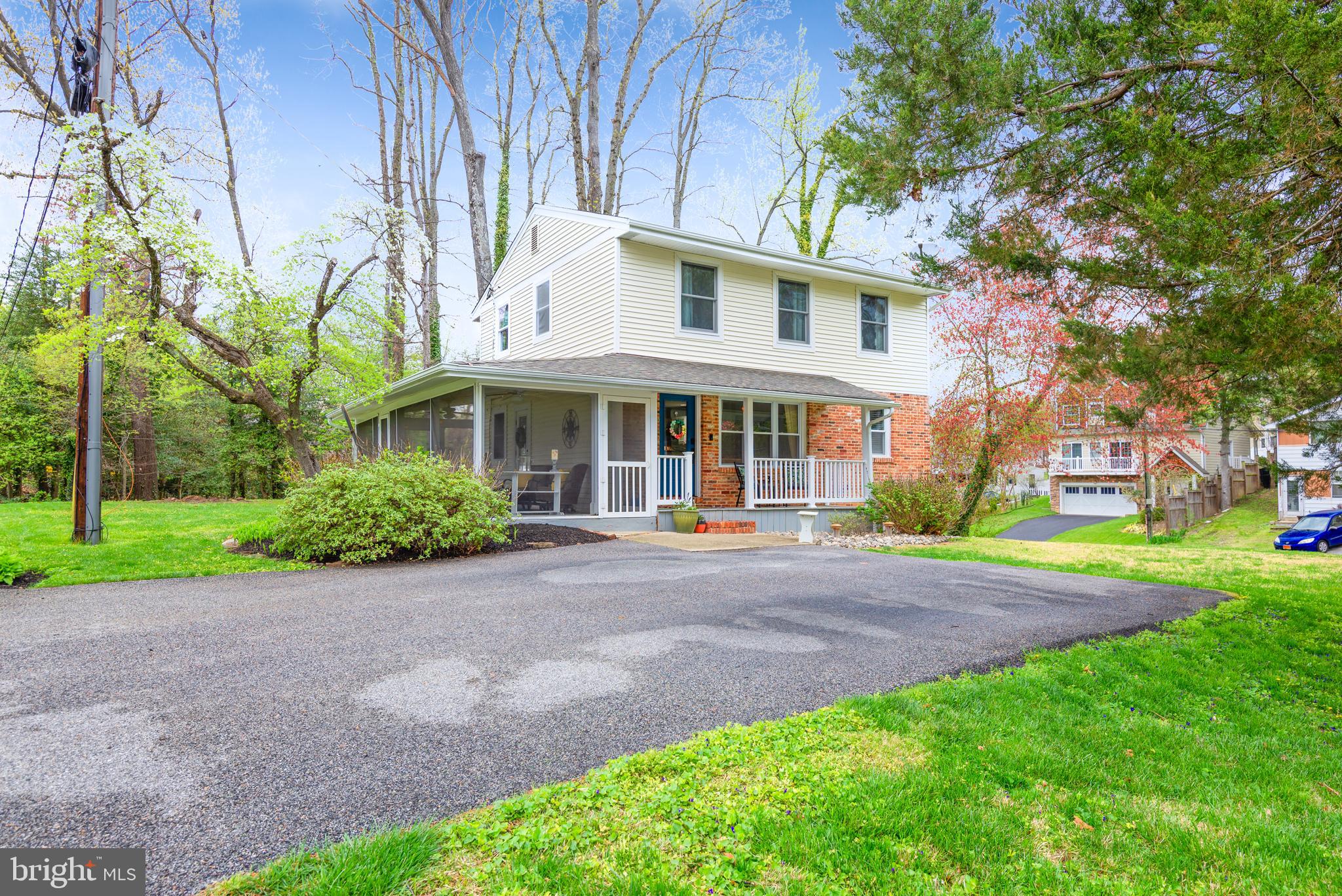 a view of a yard in front of a house with plants and large trees