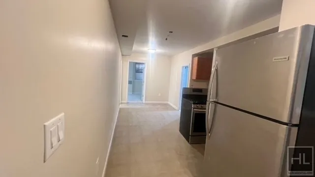a view of a refrigerator in kitchen and an empty room