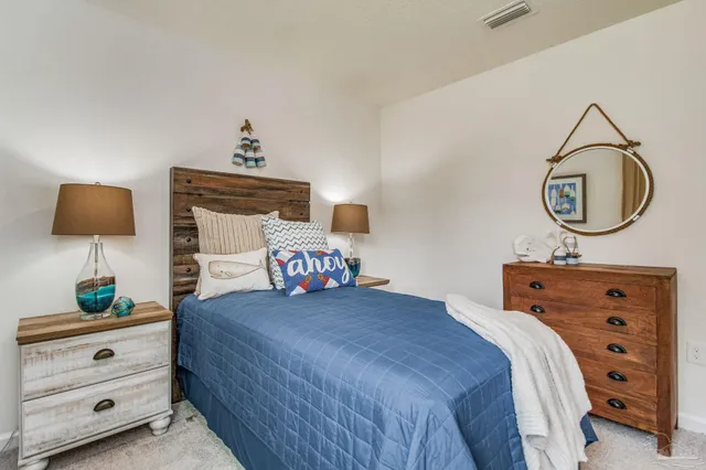 a bedroom with a bed and a lamp on dresser