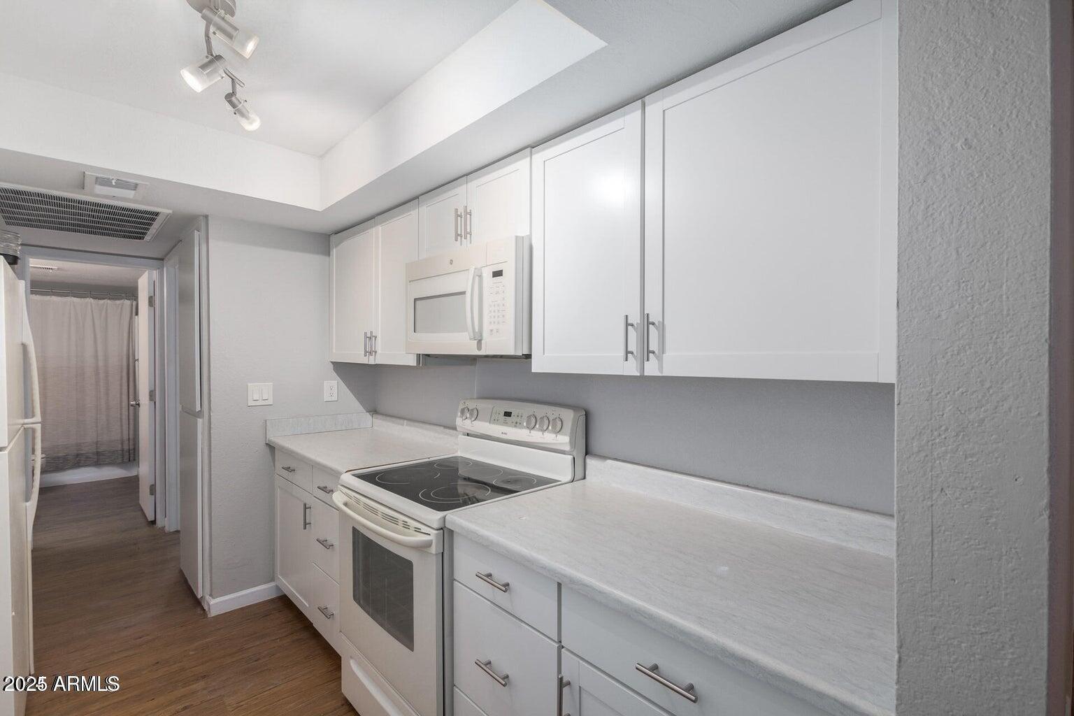 18202 North Cave Creek Road, Unit 134 Phoenix, AZ 85032 - Photo 1 of 10 a kitchen with white cabinets and white appliances