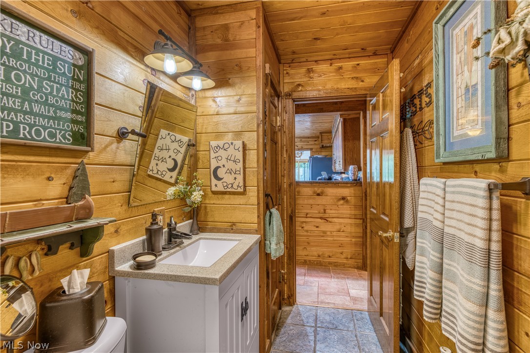 55265 Jim Ball Road Senecaville, OH 43780 - Photo 20 of 44 Bathroom with tile flooring, oversized vanity, wood ceiling, wood walls, and toilet