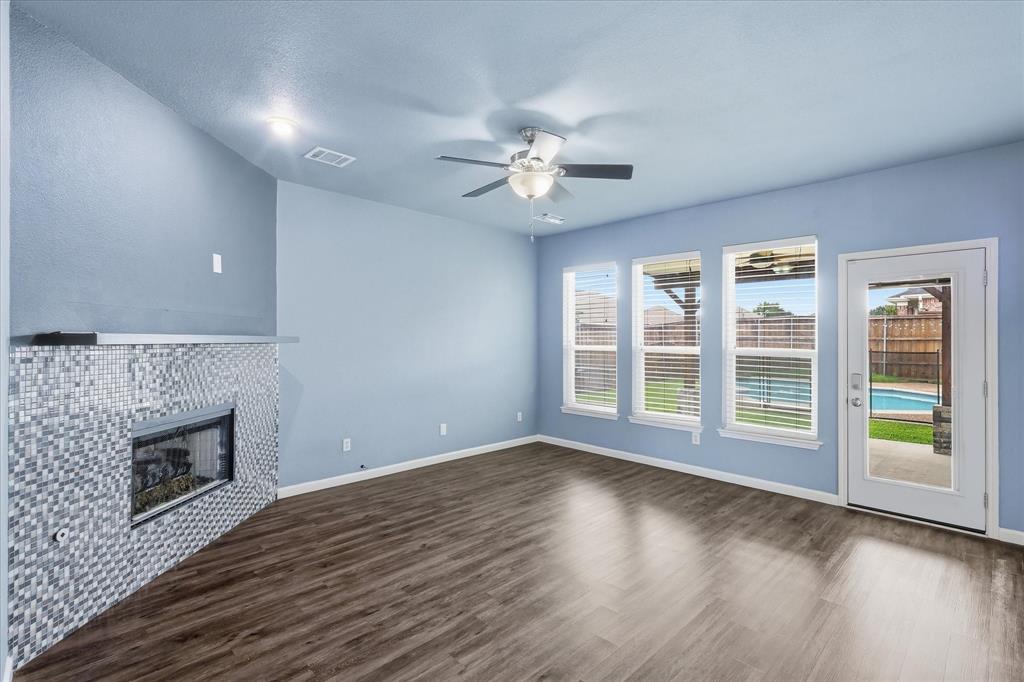 4545 Ridgepointe Drive The Colony, TX 75056 - Photo 6 of 37 Spacious living area featuring wood-finish flooring, a tiled fireplace, and a ceiling fan