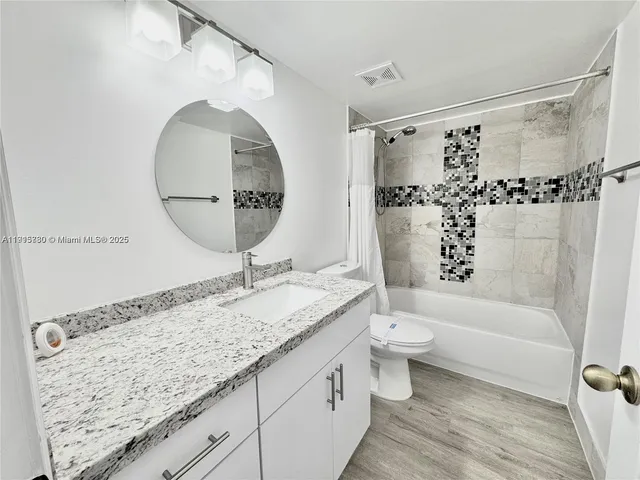 a bathroom with a granite countertop sink a toilet and a bathtub