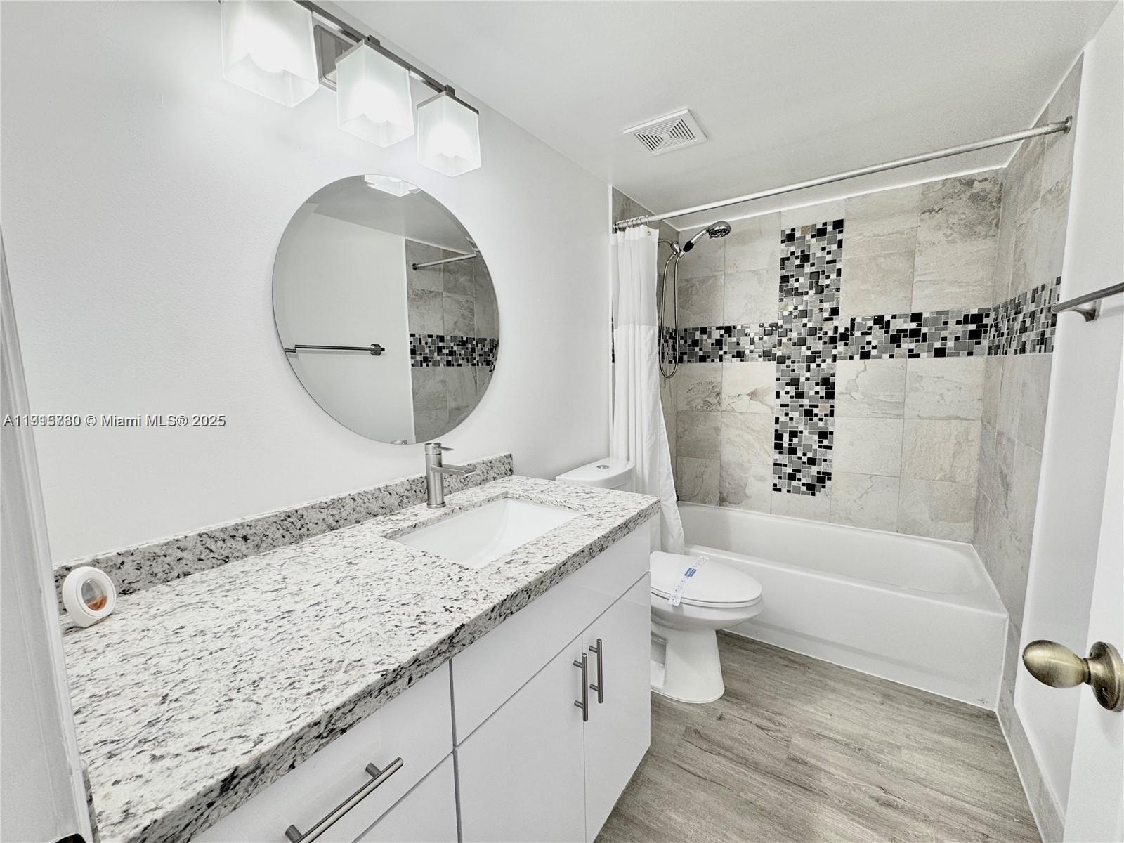 677 Southwest 111th Avenue, Unit 303 Pembroke Pines, FL 33025 - Photo 16 of 19 a bathroom with a granite countertop sink a toilet and a bathtub