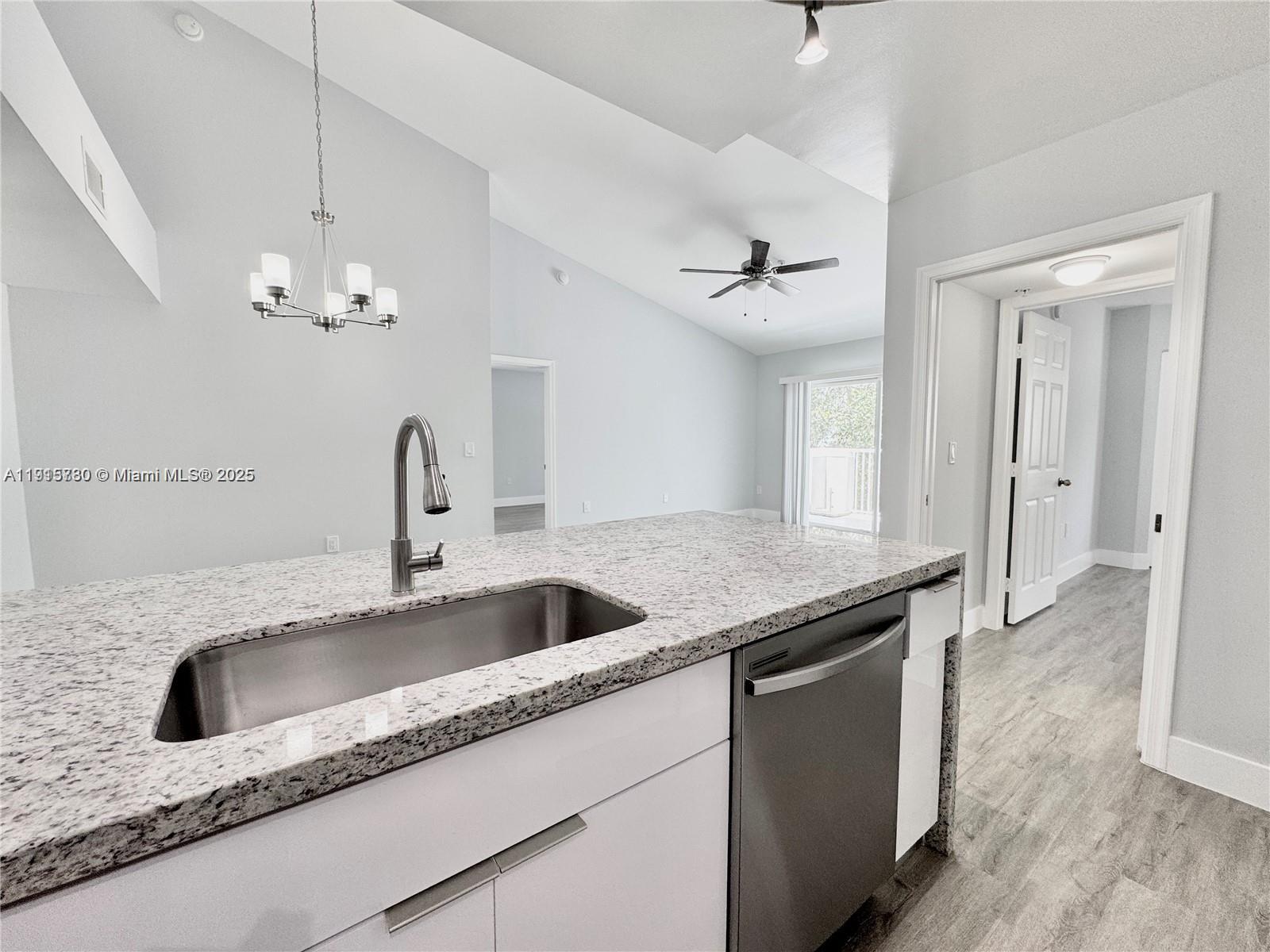 677 Southwest 111th Avenue, Unit 303 Pembroke Pines, FL 33025 - Photo 5 of 19 a kitchen with granite countertop a sink and a refrigerator