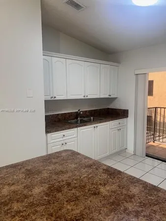 a kitchen with granite countertop a stove a sink and white cabinets