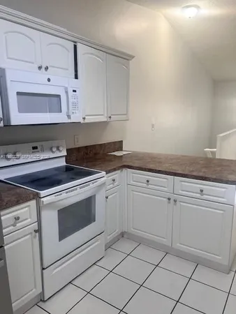 a kitchen with white cabinets and white appliances
