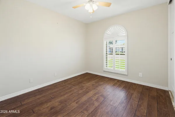an empty room with wooden floor and fan