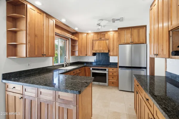 a kitchen with granite countertop a refrigerator a stove and wooden cabinets