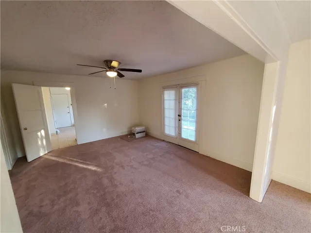 an empty room with windows and ceiling fan
