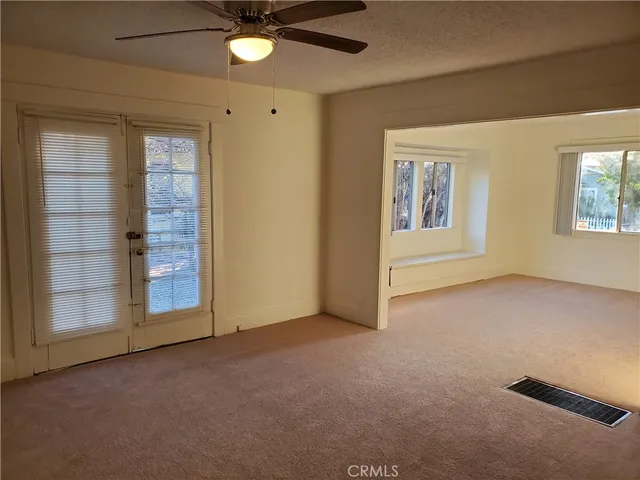 an empty room with windows and fan