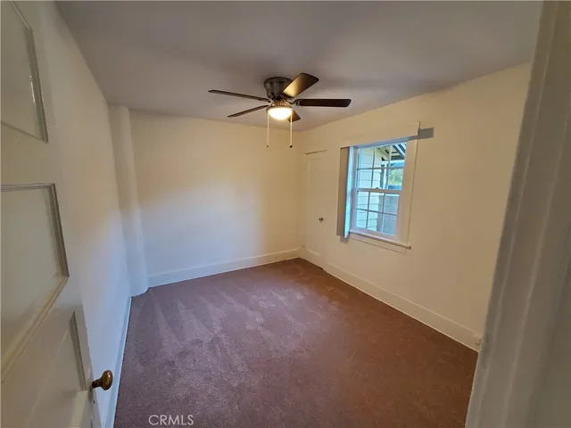 an empty room with a window and a fan