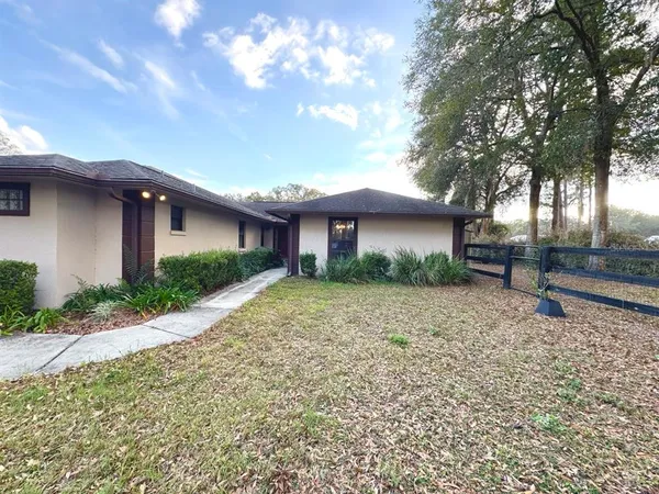 a view of a house with a yard and large tree