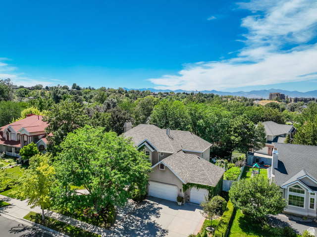 7740 Keswick Road Sandy, UT 84093 - Photo 62 of 74 Property exterior featuring a multi-level roofline, attached two-car garage, mature landscaping, and an expansive mountain backdrop