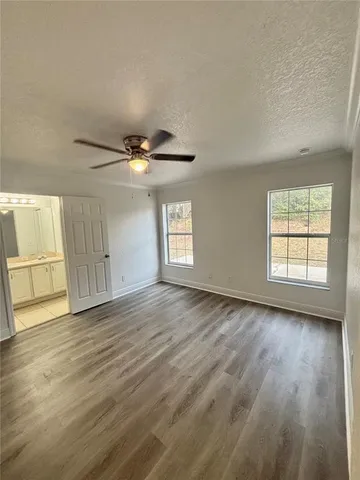 an empty room with wooden floor cabinet and windows