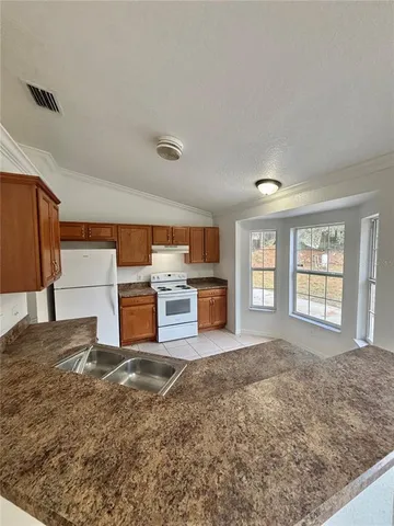 a living room with stainless steel appliances furniture windows and a kitchen view