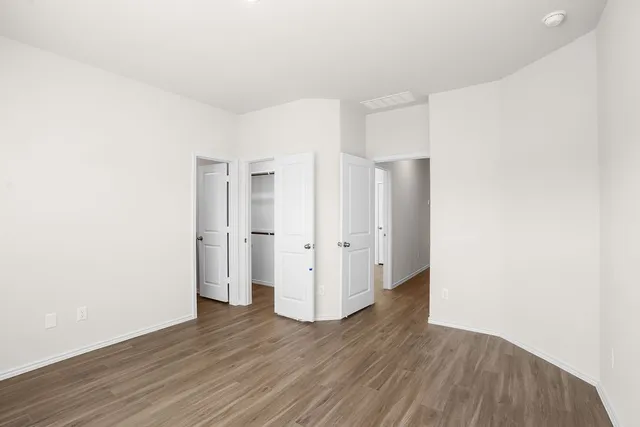 a view of an empty room with wooden floor and closet