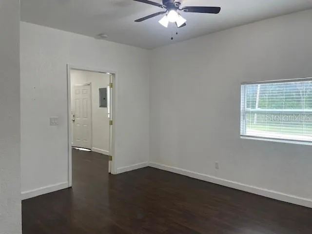 an empty room with wooden floor chandelier fan and windows