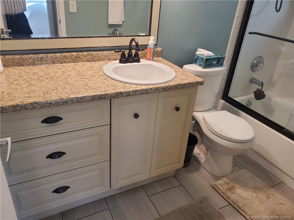 1411 Northeast 14th Court, Unit 13 Jensen Beach, FL 34957 - Photo 15 of 20 a bathroom with a granite countertop toilet sink and mirror