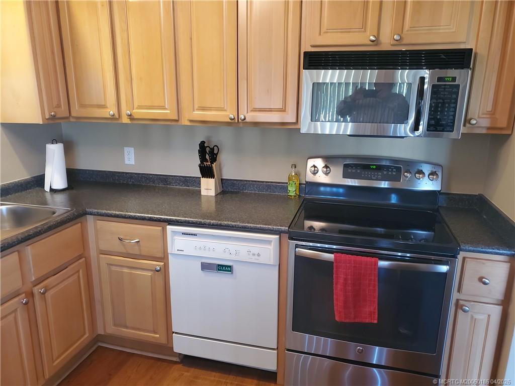 1411 Northeast 14th Court, Unit 13 Jensen Beach, FL 34957 - Photo 3 of 20 a kitchen with stainless steel appliances granite countertop a stove and a microwave