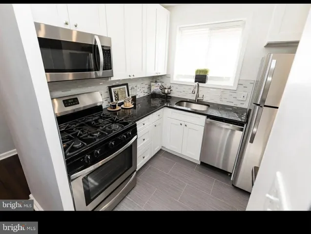 a kitchen with granite countertop a sink stove and microwave