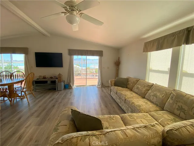 a living room with couches a flat screen tv and a large window with wooden floor