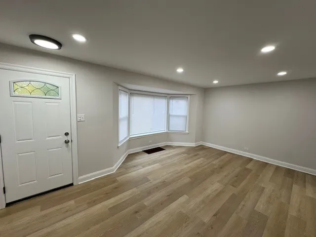 an empty room with wooden floor and window