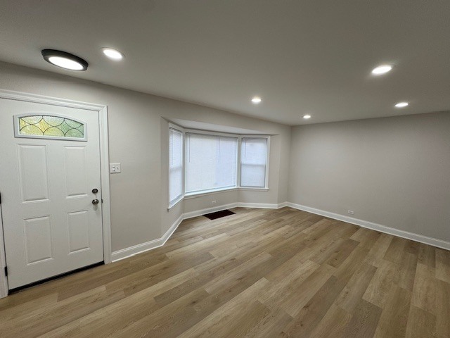 10454 South Forest Avenue Chicago, IL 60628 - Photo 3 of 16 an empty room with wooden floor and window