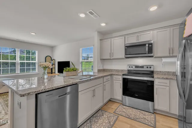 a kitchen with stainless steel appliances granite countertop a stove sink microwave and refrigerator
