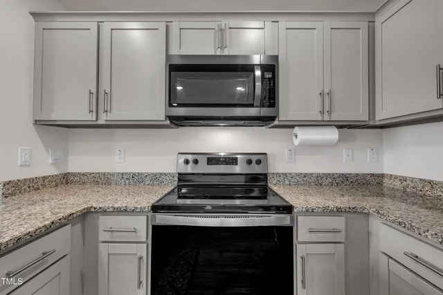 a kitchen with granite countertop white cabinets and stainless steel appliances