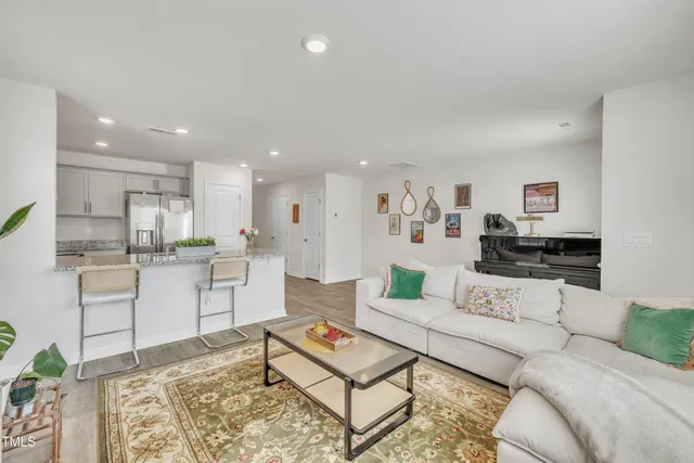 a living room with furniture a rug and kitchen view