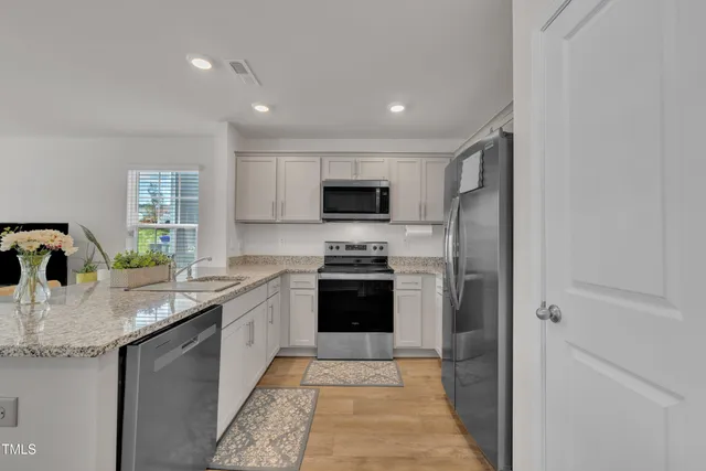 a kitchen with stainless steel appliances granite countertop a stove a sink and a refrigerator
