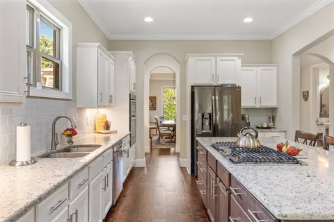 a large kitchen with stainless steel appliances granite countertop a lot of counter space and wooden floors
