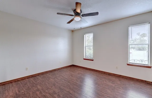 a view of empty room with wooden floor and fan