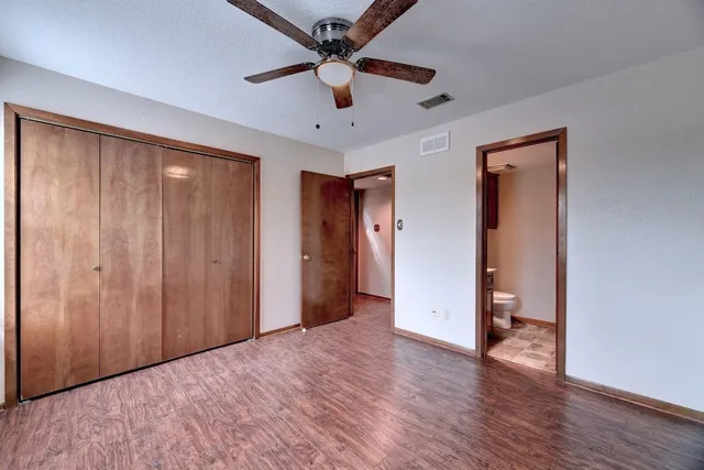 an empty room with wooden floor and a ceiling fan