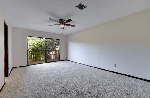 a view of a big room with windows and chandelier fan