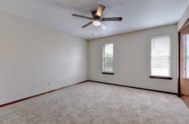 an empty room with windows and fan