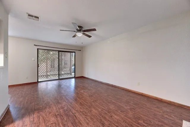 a view of an empty room with wooden floor and a window